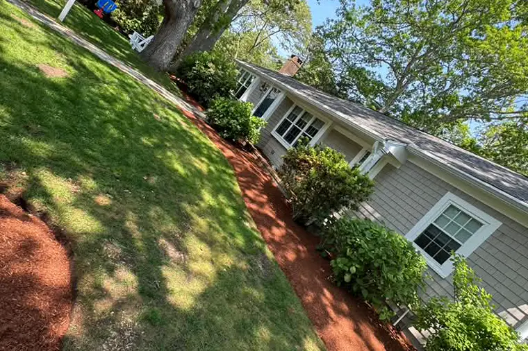 Cape Cod home with edged mulch beds and trimmed shrubs