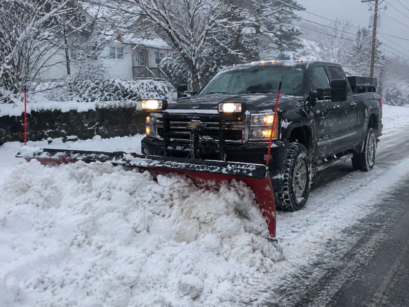 Pickup truck with a snow plow clearing a driveway in Cape Cod, MA