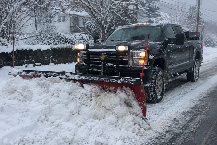 Truck with a snow plow clearing a road after a Cape Cod storm